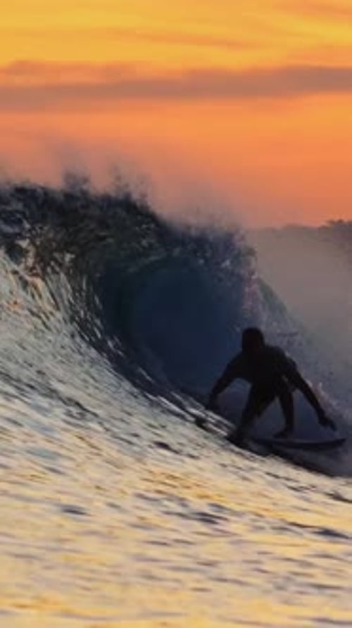 Surfer Rides Ocean Wave at Sunset