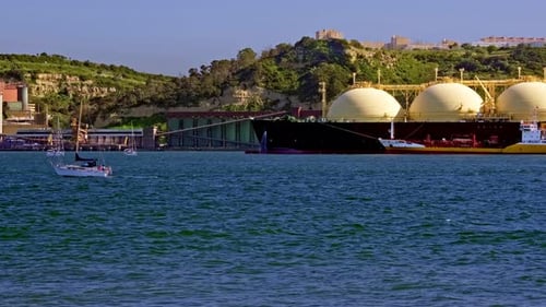 LNG Tanker Moored By Industrial Pier and Green Hill on Sunny Day