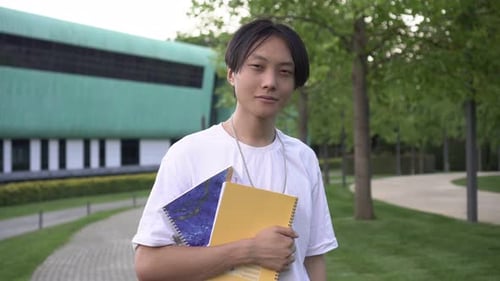 College Student With Notebooks on Sunny Campus