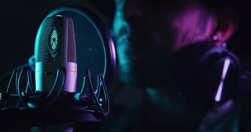 Close up of an young professional smiling energetic male singer wearing headphones is performing a