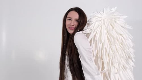 Portrait d'une femme souriante à l'image d'un ange, elle montre les mains et le cœur