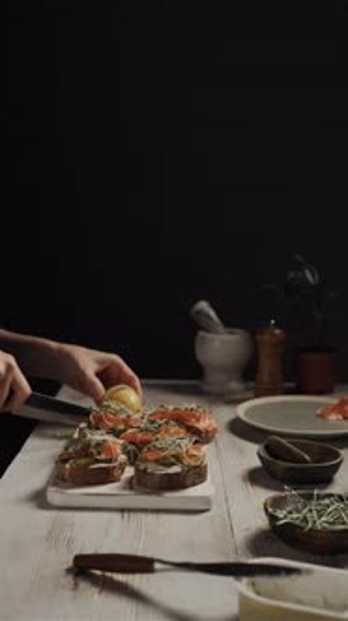 Person Squeezing Lemon Juice on Salmon Sandwich