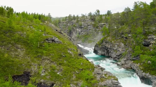 Dramatic Aerial View of a Fast River Carving Through Mountains