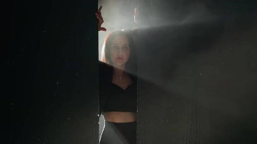 Woman Peers Through Narrow Opening in Darkness