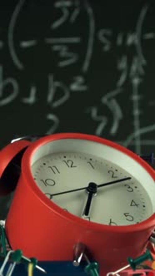 Alarm Clock and School Tools Soaring Up Against the Blackboard Background Filmed on a Highspeed