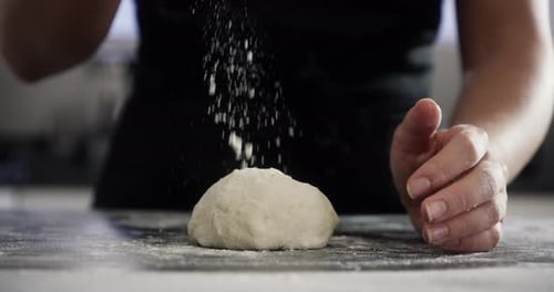 4k video footage of an unrecognizable woman sprinkling flour on her dough