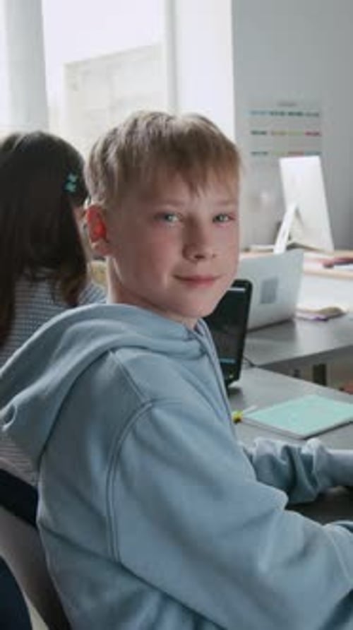 Portrait of Smiling Boy Sitting at Desk During Class in School