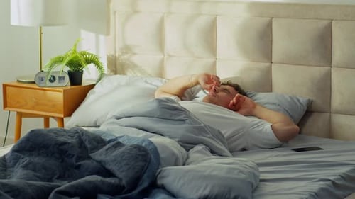 Man Wakes up and Stretches in Bed