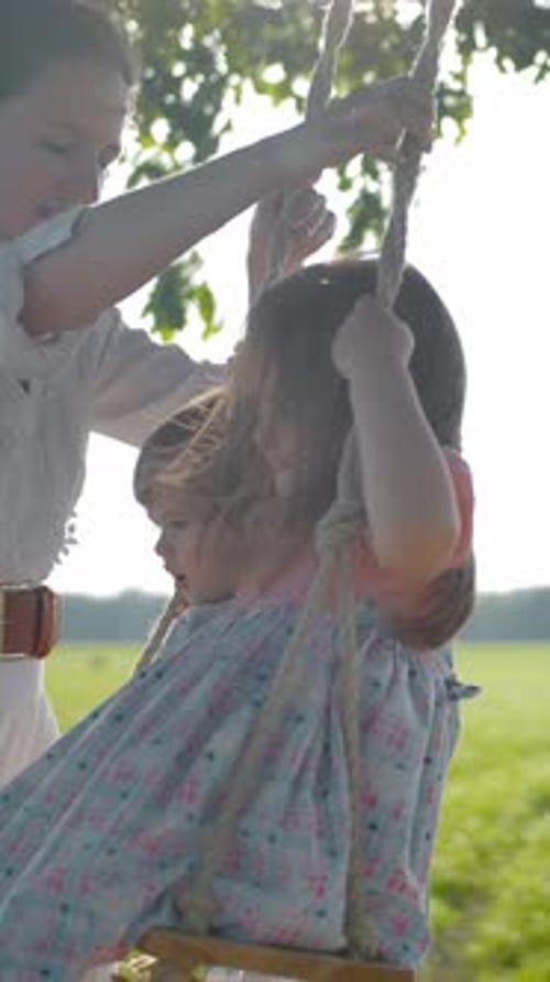 Mother Swings Daughters on Rustic Rope Swing