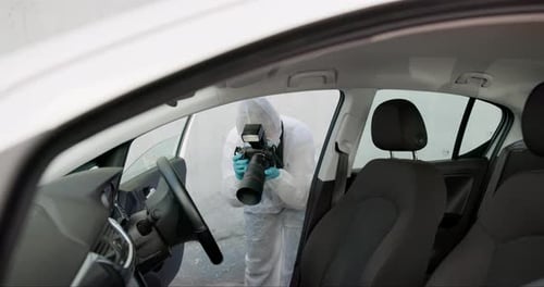 Individual in Hazmat Suit Taking Photos in a Car