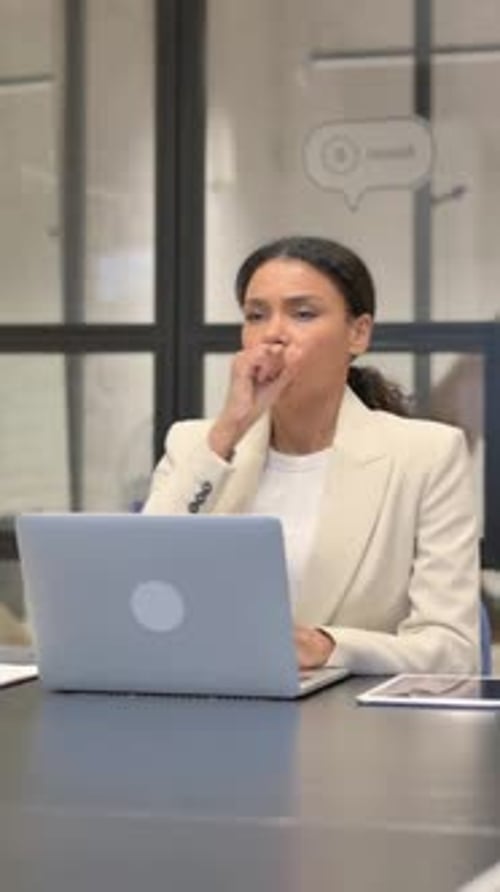 Businesswoman Coughing While Working on Laptop Indoors