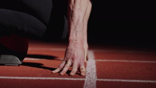 Runner Standing On Start Of Sprinter Lane In Stadium Closeup View Of Male Hands On Floor