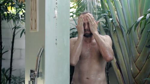 Man in Exotic Outdoor Shower Cleansing Face