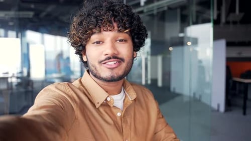 POV Webcam view. Handsome smiling employee talking on a video call using a smartphone while standing