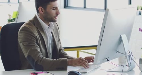 4K video footage of a young designer working at his computer in a modern office