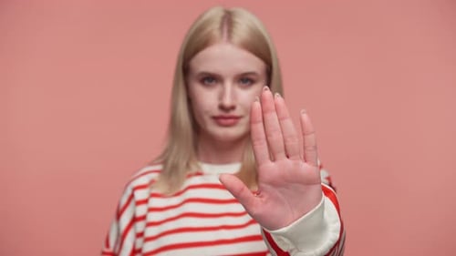 Serious Young Woman Making Stop Hand Gesture on Pink
