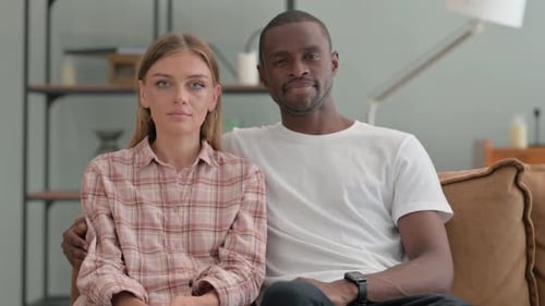 Serious Interracial Couple Looking at Camera at Home