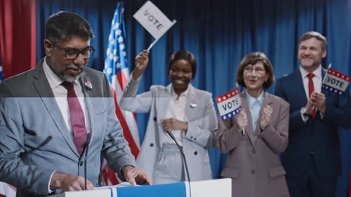 Political Speaker Addresses Crowd at Podium with Flags