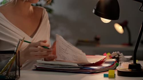 Workaholic-Frau sitzt am Schreibtisch und signiert Papierblätter im überladenen Stapel bunter Akten