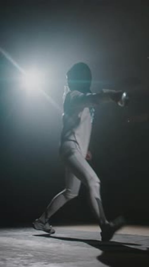 Vertical of Foilswoman Fighting on Rapier in Dark Hall