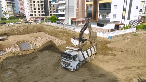 Excavator Fills Dump Truck on Urban Construction Site