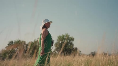 Confident Woman in Green Dress Walking Through Tall Grass Field