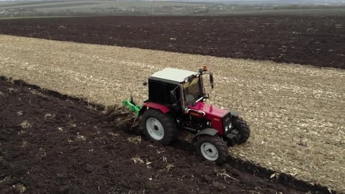 Red tractor plowing the field in Ukraine