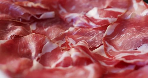 Macro of spinning thin slices of pork ham on the dish (close up)