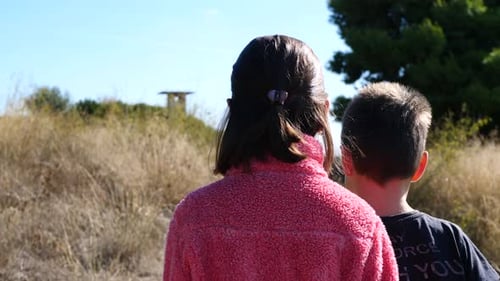 Brother and sister walking together on a path. Slow-motion gimbal shot.