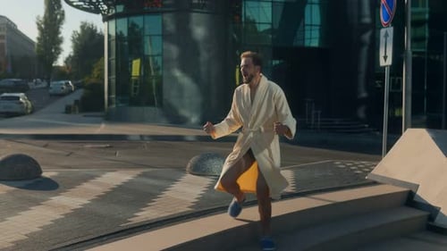 Energetic Young Man in Bathrobe Jumping Outdoors with Playful Excitement