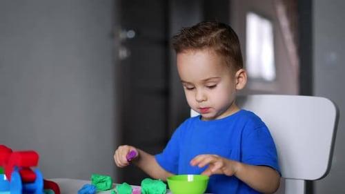 Boy Playing with Playdough at Table Indoors