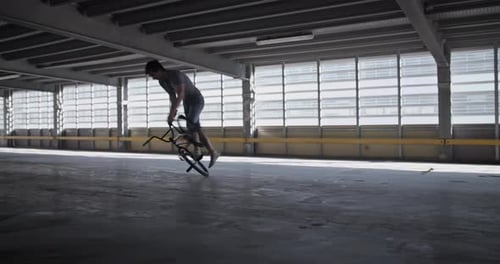 Energetic Sportsman Performing BMX Trick in Parking Lot