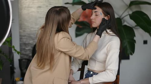 Makeup Artist Applying Eyebrow Tint to Young Woman