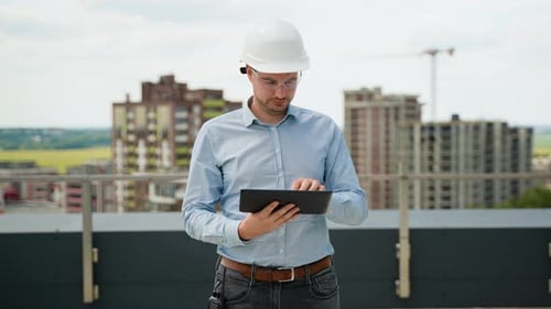 Construction Engineer Using Tablet for Project Supervision on Rooftop Site