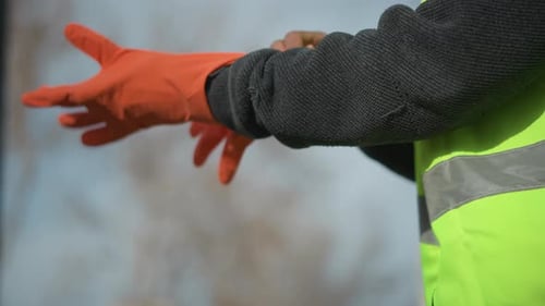 Primer plano de un trabajador con un suéter oscuro y un chaleco de alta visibilidad