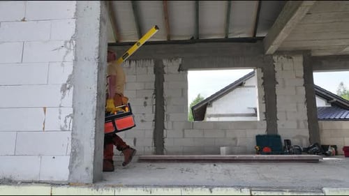 Construction Worker Holding Tool in Front of Building