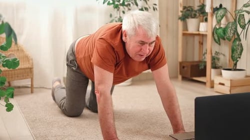 Hombre mayor maduro feliz haciendo ejercicios de gimnasia en casa en línea con una computadora portátil Estilo de vida saludable