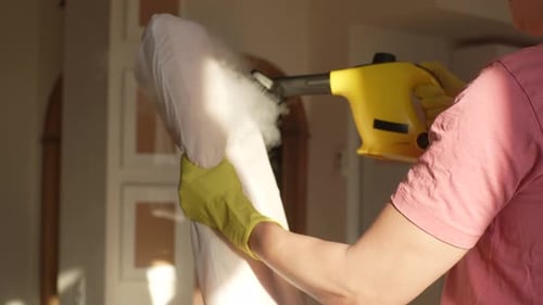 Woman Steaming Cushion with Yellow Handheld Cleaner