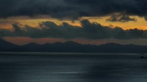 Dramatisch Sonnenuntergang über dem Meer und der Bergsilhouette.
