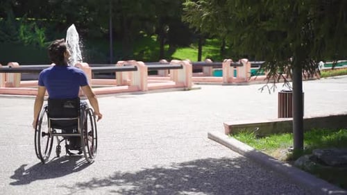 Young disabled person walking in wheelchair in city park in slow motion.
