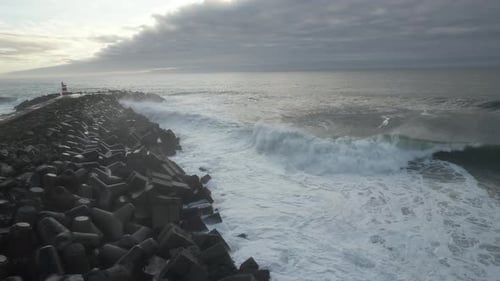 Waves Crashing Against Breakwater with Lighthouse