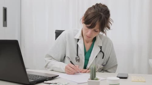 Professional Female Doctor Writing Medical Prescription On The Clinic Table. medium shot