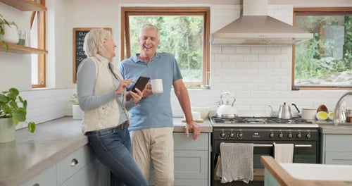 Smiling Couple Looks at Phone in Bright Kitchen