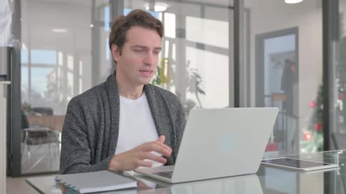 Excited Young Man Celebrating Success on Laptop in Office
