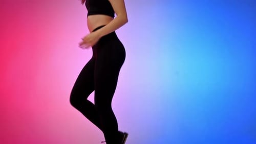 Young smiling woman in a tracksuit in virtual reality VR headset jogging in a studio with blue and r