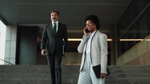 Businesswoman Walking and Talking on Phone Outside Office