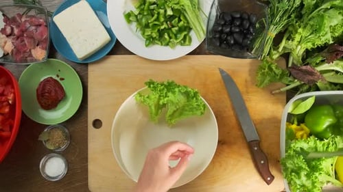 Bol avec laitue, arrangé pour la garniture, feta, olives, légumes, viande sur table