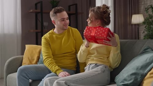 Happy Couple with Present on the Sofa Indoors