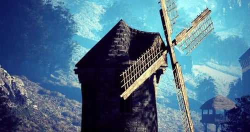 Historic Windmill Stands Against a Serene Mountain Backdrop During Daylight