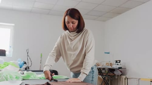 Creative Woman Cutting Fabric Design Pattern in Sewing Workshop